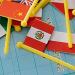Bandeiras em miniatura dispostas sobre um mapa-múndi, representando relações internacionais e cooperação entre países.