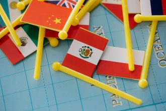 Bandeiras em miniatura dispostas sobre um mapa-múndi, representando relações internacionais e cooperação entre países.