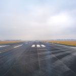 Pista de aeroporto vazia vista à distância em um dia de névoa.