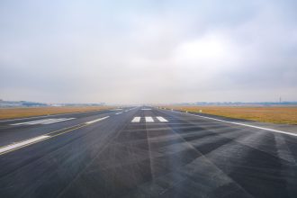 Pista de aeroporto vazia vista à distância em um dia de névoa.