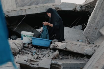 Mulher lava roupas entre escombros em Gaza.